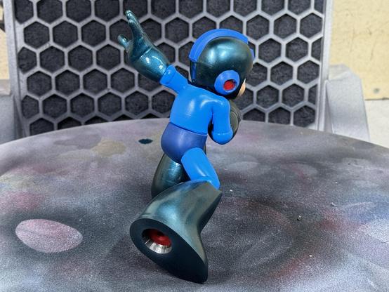 A 3d printed figure of Capcom‘s Mega Man. Hands, feet and helmet are painted in candy cobalt blue. Here the figure is shown from the back