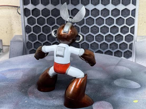 A 3d printed figure of Capcom‘s Cut Man. Hands, feet and helmet are painted in candy ruby red. Here the figure is shown from the back.