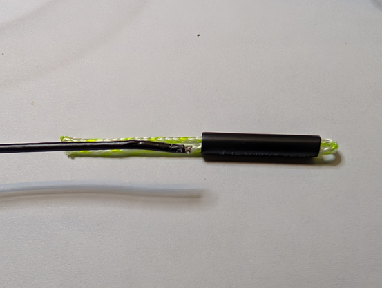 A piece of wire next to the tails of the doubled dacron line, ready to be inserted into the heat shrink