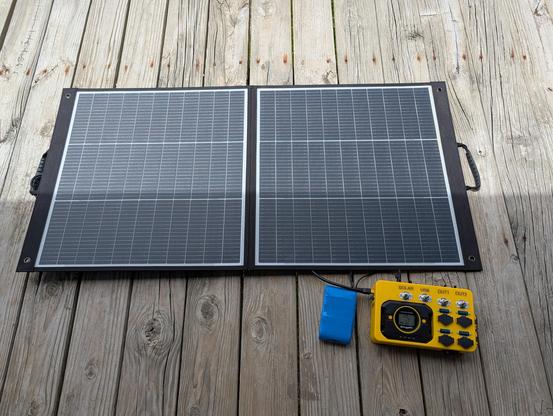 Image of small battery, charger controller, and solar panel. The solar panel is one third shaded.