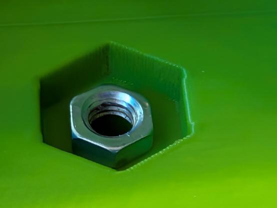 Photograph of an M5 nut sitting inside a much-too-big hole in which it was intended to be captive.